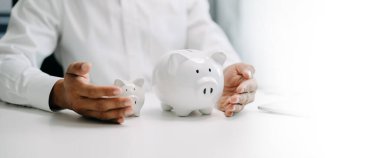 Asyalı Adam, kar amaçlı büyüyen ve gelecek için para biriktiren bir iş için domuz kumbarasına para koyuyor.