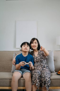 Anne ve oğlu kanepede oturup bilgisayar oyunu oynuyorlar. 