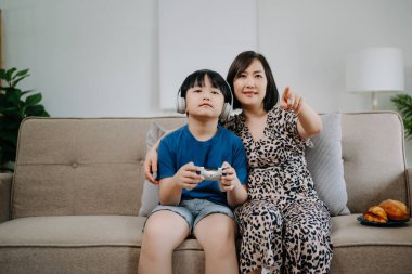 Anne ve oğlu kanepede oturup bilgisayar oyunu oynuyorlar. 