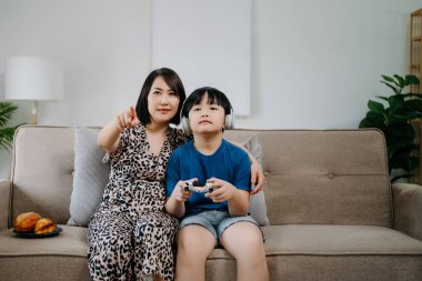 Anne ve oğlu kanepede oturup bilgisayar oyunu oynuyorlar. 