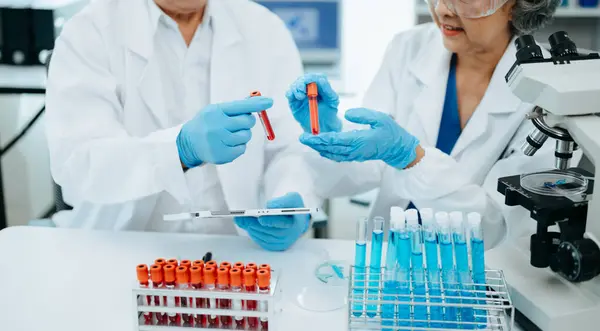 Senior scientists conducting research investigations in a medical laboratory, a researcher in the foreground is using a microscope in laboratory for medicine.