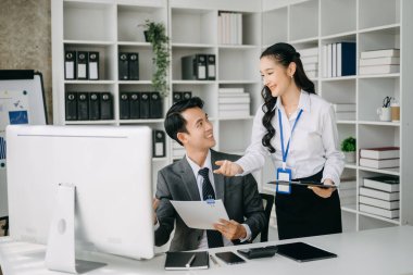 Modern ofis odasında bilgisayar kullanan Asyalı iş adamı ve bayan meslektaşı. Takım çalışması, finansal pazarlama ekibi.