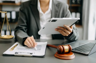 Adalet ve hukuk kavramı. Tokmak mahkeme salonunda beyaz masada dijital tablet bilgisayarla çalışan bir erkek yargıç. 