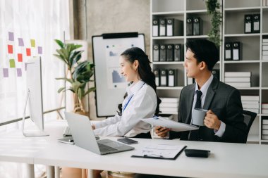 Ev ofisinde dizüstü bilgisayar kullanan iki Asyalı iş adamı.