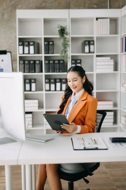 İş kadını ofis masasında dijital tableti finans raporu olarak kullanıyor. Ofiste analitik araştırma kavramı