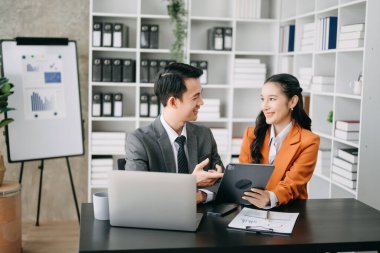Modern ofis odasında dizüstü bilgisayar kullanan Asyalı iş adamı ve bayan meslektaşı. Takım çalışması, finansal pazarlama ekibi.