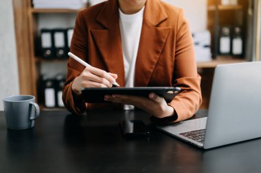 Ofiste dijital tablet üzerinde çalışan kadın ve ofiste grafikler.