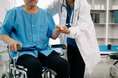 Asyalı fizyoterapist yaşlı bir adama hastanede yardım ediyor.