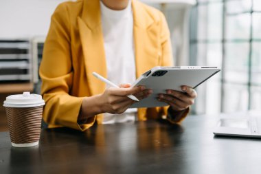 İş kadını modern ofiste oturuyor ve tablet kullanıyor. 