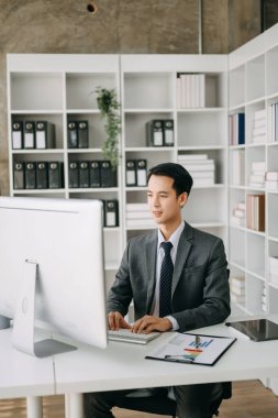 Modern ofis odasında bilgisayar kullanan Asyalı bir işadamı. Takım çalışması, finansal pazarlama ekibi.