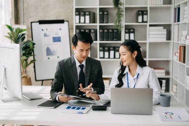 Ev ofisinde dizüstü bilgisayar kullanan iki Asyalı iş adamı.