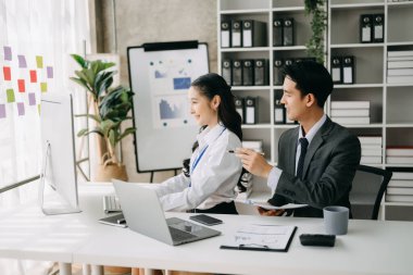 Ev ofisinde dizüstü bilgisayar kullanan iki Asyalı iş adamı.