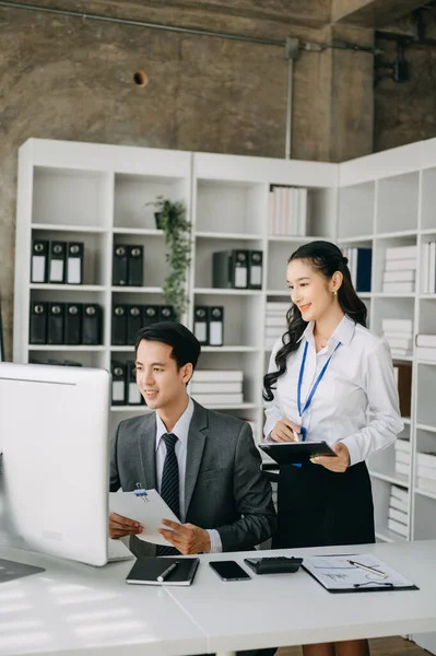 Modern ofis odasında bilgisayar kullanan Asyalı iş adamı ve bayan meslektaşı. Takım çalışması, finansal pazarlama ekibi. 