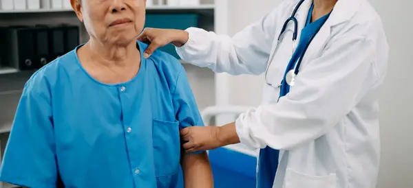 アジアの理学療法士 病院で腕を伸ばす高齢者の患者を助ける — ストック写真