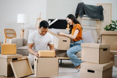 Mutlu Asyalı genç ve çekici çift büyük kutularla yeni bir eve taşınıyor.