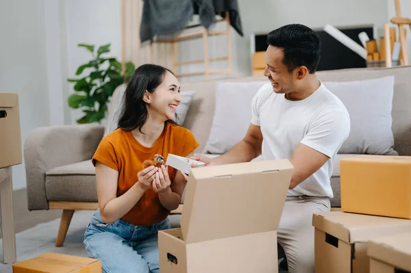 Young couple with big boxes moving into a new house. Asian man and woman helping to lift boxes for the new home