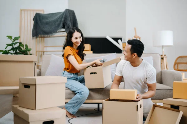 Young couple with big boxes moving into a new house. Asian man and woman helping to lift boxes for the new home