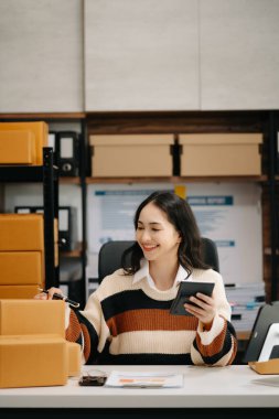 Güzel Asyalı bayan blogcu dijital tablette video kaydına kamera önünde kıyafetlerini gösteriyor, dükkanında canlı yayın yapıyor. Çevrimiçi Alışveriş Arabası kavramı