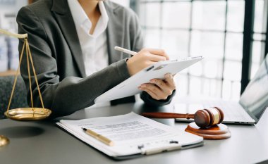 Adalet ve hukuk kavramı. Mahkeme salonundaki erkek yargıç tokmak, akıllı telefon, dizüstü bilgisayar ve dijital tablet bilgisayarla beyaz masada çalışıyor.