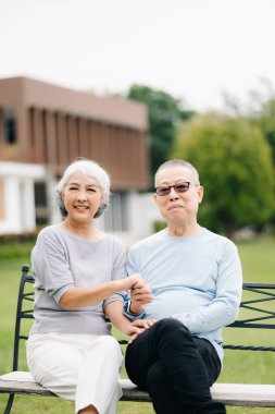 Asyalı son sınıf çifti iyi vakit geçiriyor. Onlar parkta bankta otururken gülüyor ve gülümsüyorlar. Hoş yaşlı çift.