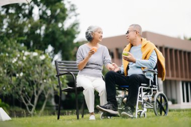 Asyalı son sınıf çifti iyi vakit geçiriyor. Onlar parkta bankta otururken gülüyor ve gülümsüyorlar. Hoş yaşlı çift.