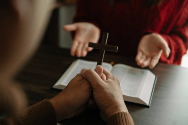 Çarmıhlı kadın eli. Umut, inanç, Hıristiyanlık, din, kilise kavramı ve Tanrı 'ya dua. Tahta masada!