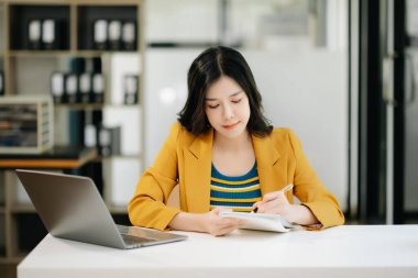 Modern ofiste dizüstü bilgisayarda çalışan genç ve güzel bir kadın.