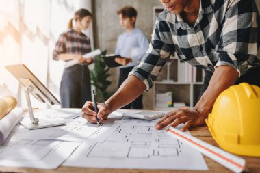 Üç mimar yeni projeyi tartışıyor. Genç erkekler ve kadınlar yeni bir bina oluşturmak için birlikte çalışıyorlar.