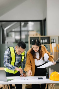Müteahhit ve mimar büyük bir proje üzerinde çalışıp çalışmayacaklarını araştırıyor. İnşaat ofisindeki bina