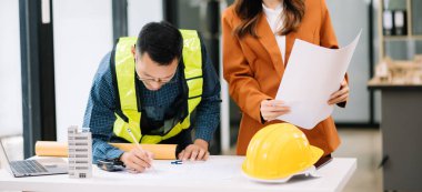 Müteahhit ve mimar büyük bir proje üzerinde çalışıp çalışmayacaklarını araştırıyor. İnşaat ofisindeki bina