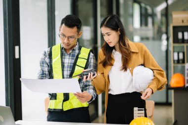 Müteahhit ve mimar büyük bir proje üzerinde çalışıp çalışmayacaklarını araştırıyor. İnşaat ofisindeki bina