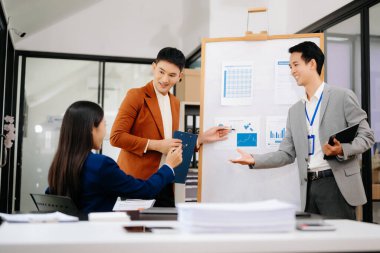 Bir grup genç Asyalı iş adamı yaratıcı iş ofisinde modern girişimin iş planını tartışıyor.