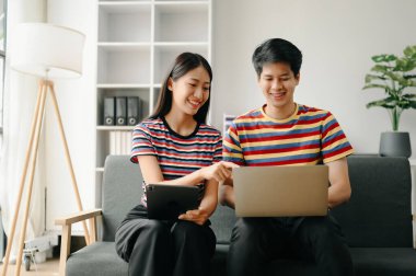 İki Asyalı öğrenci evdeki oturma odasında online olarak birlikte öğreniyor.