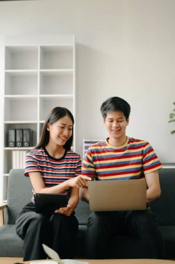 İki Asyalı öğrenci evdeki oturma odasında online olarak birlikte öğreniyor.