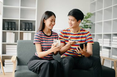 İki Asyalı öğrenci evdeki oturma odasında online olarak birlikte öğreniyor.