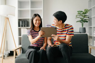 İki Asyalı öğrenci evdeki oturma odasında online olarak birlikte öğreniyor.