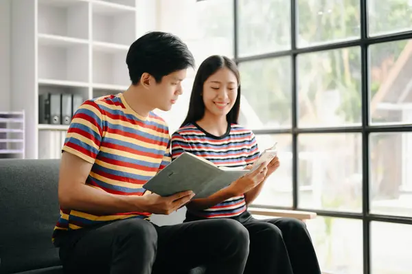 Two asian students learning together online together in living room at home