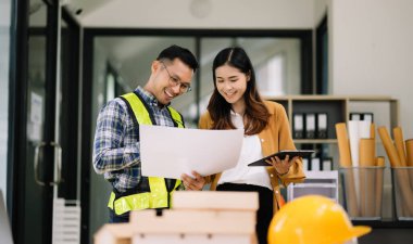 Müteahhit ve mimar büyük bir proje üzerinde çalışıp çalışmayacaklarını araştırıyor. İnşaat ofisindeki bina