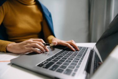 İş kadını elleri ofiste dizüstü bilgisayarla ve mali iş stratejisiyle çalışıyor.