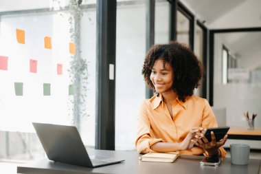 Bir ofis masasında, vergi, rapor, muhasebe, istatistik ve analitik araştırma konseptinde matematik finansmanı için dizüstü bilgisayar kullanan Afrikalı kadın.
