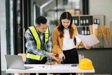 Müteahhit ve mimar büyük bir proje üzerinde çalışıp çalışmayacaklarını araştırıyor. İnşaat ofisindeki bina