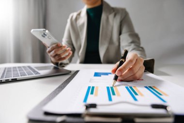 İş kadını elleri ofiste dizüstü bilgisayarla ve mali iş stratejisiyle çalışıyor.