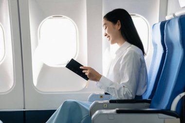 Çekici Asyalı kadın yolcu rahat koltukta otururken elinde not defteri tutuyor. Stil olarak seyahat et