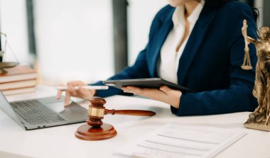 Adalet ve hukuk kavramı. Dijital tablet üzerinde çalışan tokmak mahkeme salonundaki kadın yargıç. 