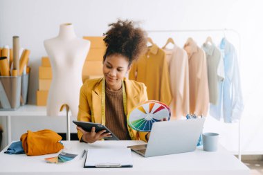 Afrikalı terzi kadın terzide terzilik yapıyor. Güzel genç bayan moda tasarımcısı gülümsemesi ve Studi 'deki başarıdan sonra