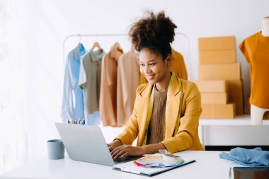 Afrikalı terzi kadın terzide terzilik yapıyor. Güzel genç bayan moda tasarımcısı gülümsemesi ve Studi 'deki başarıdan sonra