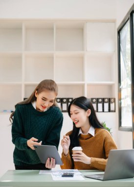 Ofiste dijital tablet bilgisayar kullanan iki Asyalı iş adamı