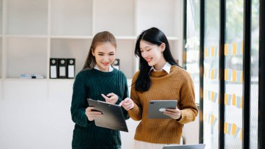 Ofiste dijital tablet bilgisayar kullanan iki Asyalı iş adamı