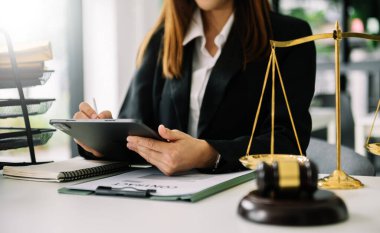 Adalet ve hukuk kavramı. Kadın avukat mahkeme salonunda çalışıyor ve yargılıyor tokmak, dijital tablet bilgisayar üzerinde çalışıyor.