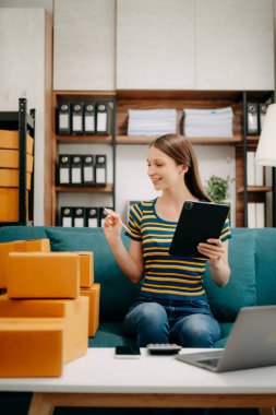 Başlangıçta küçük işletme KOBİ 'si, girişimci sahibi kadın paket ürün kutularını hazırlamak için online alışveriş siparişi alıyor ve kontrol ediyor
